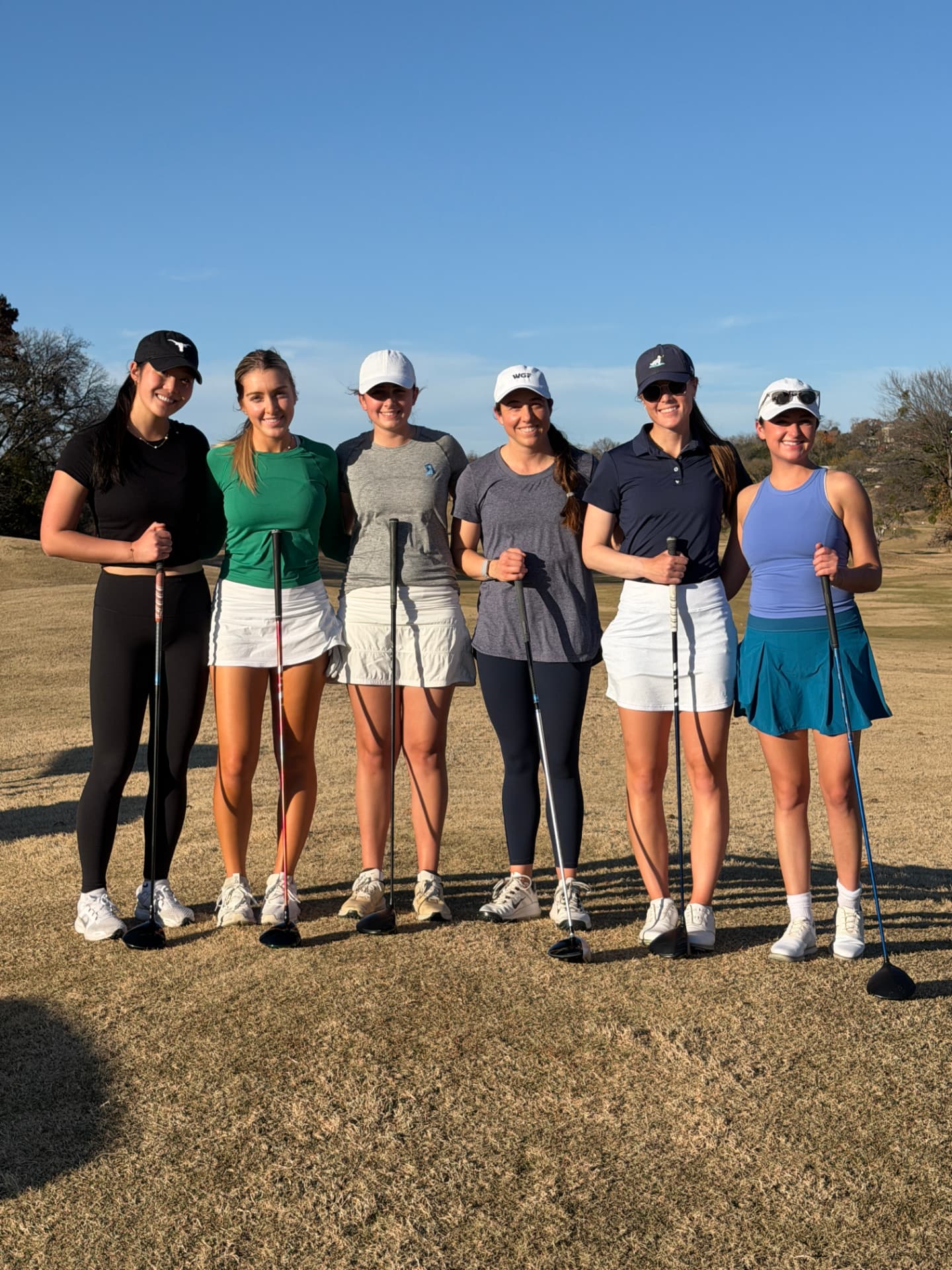 Six college golfers standing together on the fairway at a past retreat