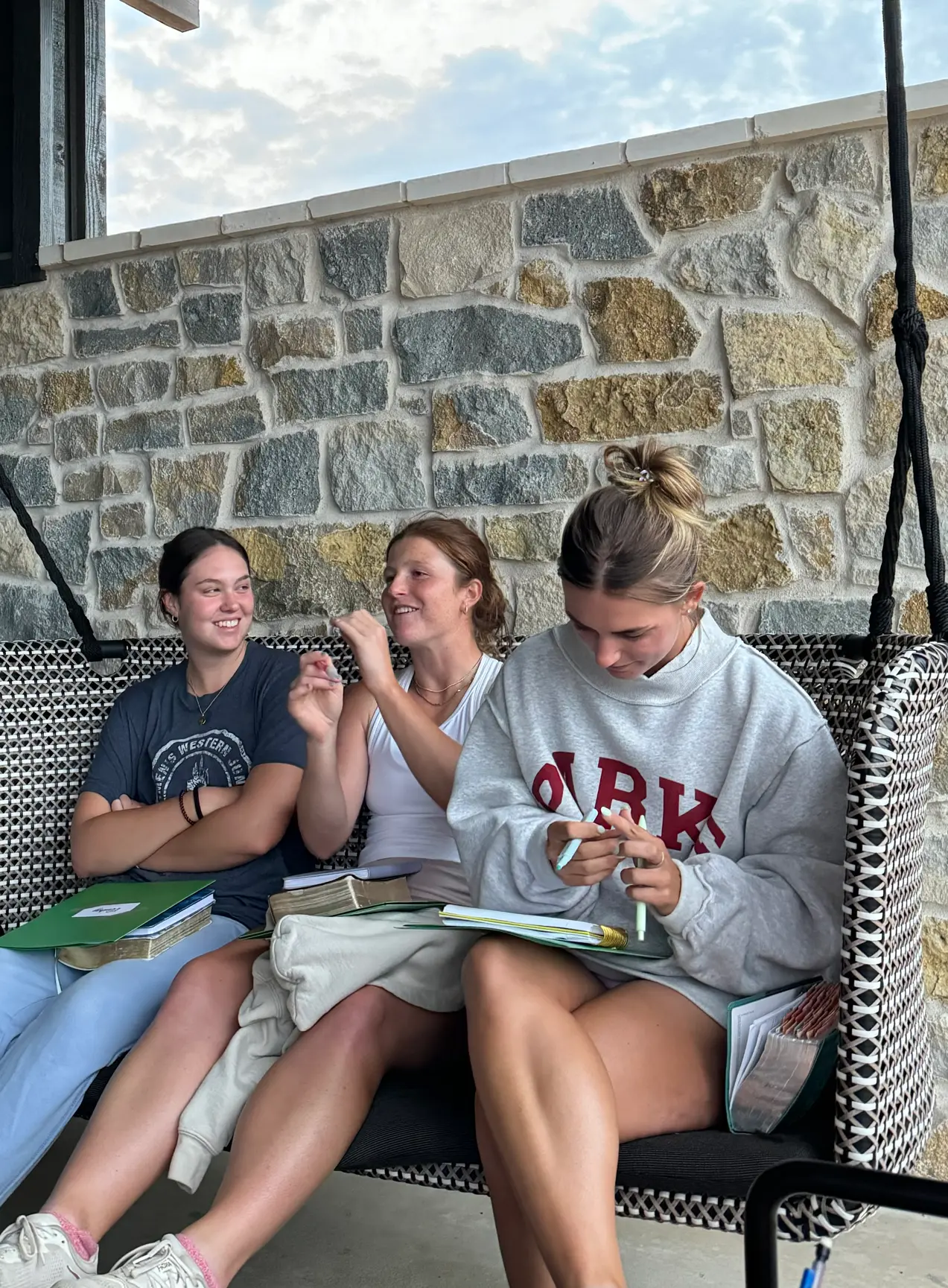 Three golfers laughing together on a porch swing with their Bibles and study books