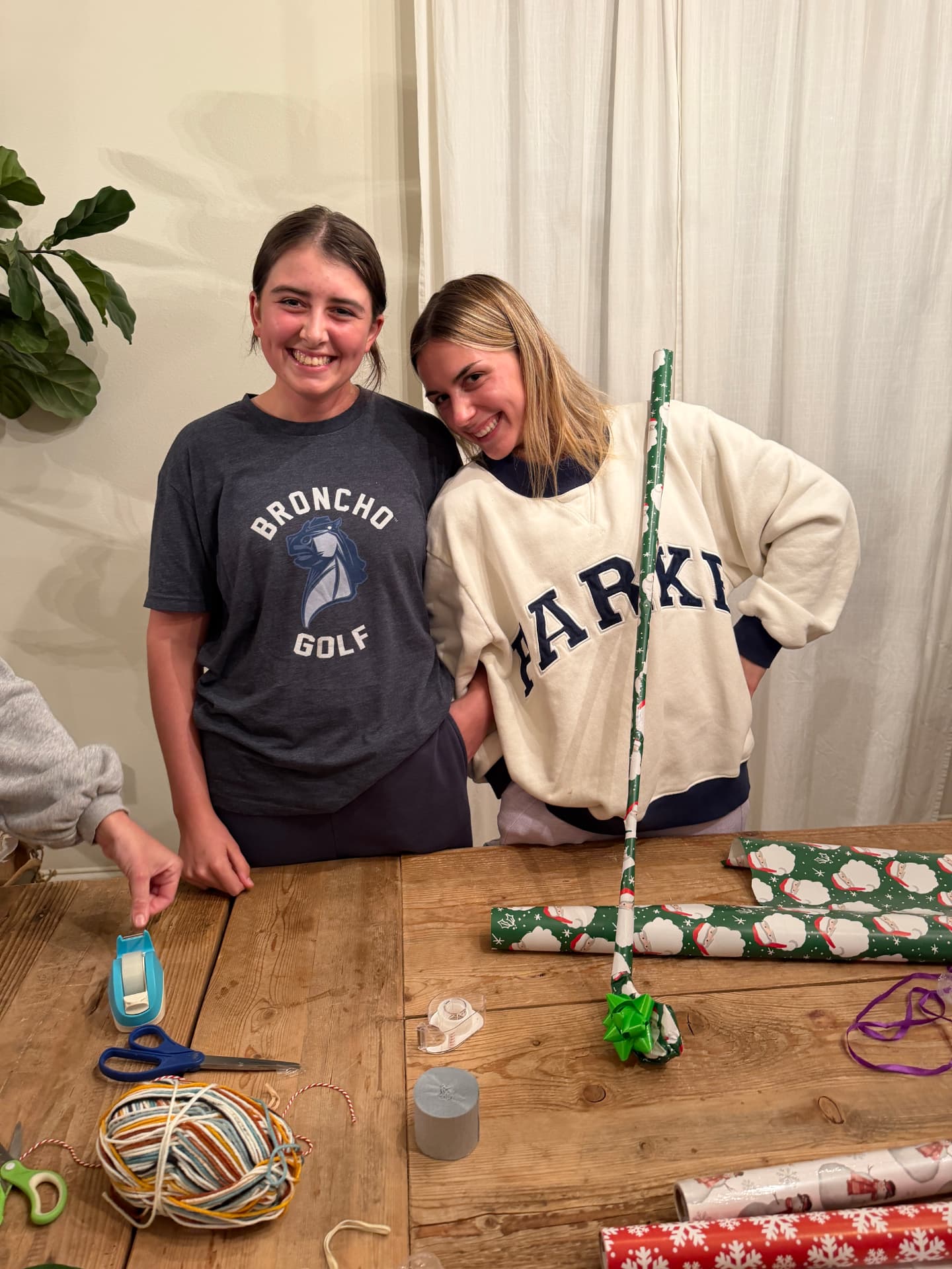 Two golfers laughing while wrapping gifts together
